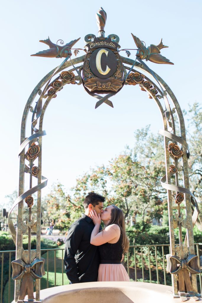 Couple kissing under archway in Magic Kingdom