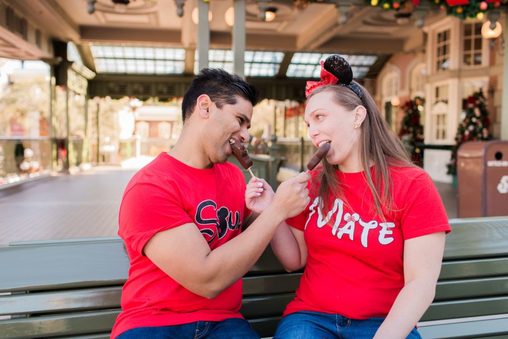 Couple feeding each other treats in Magic Kingdom Engagement shoot