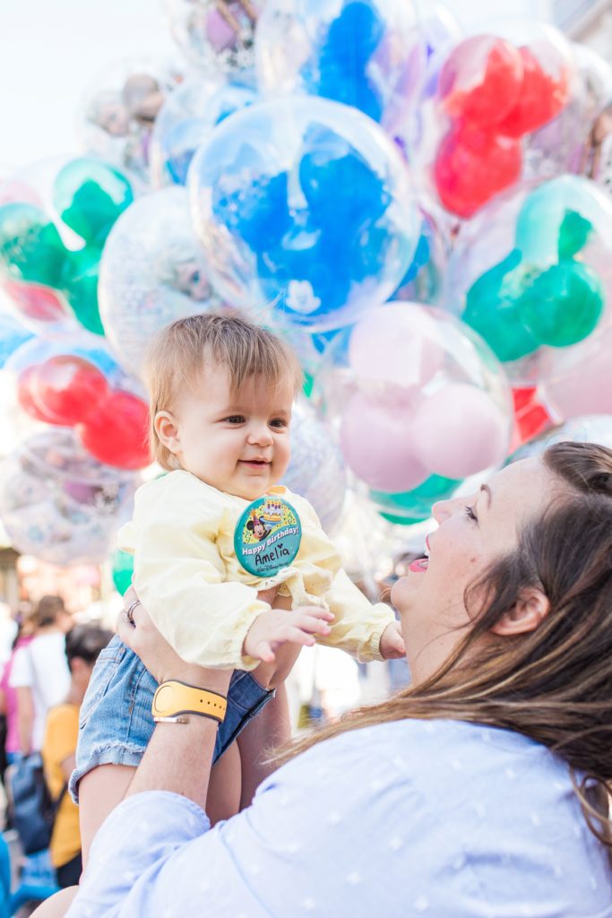 1 year old girl smiling in front of Disney ballons Disney photo prop