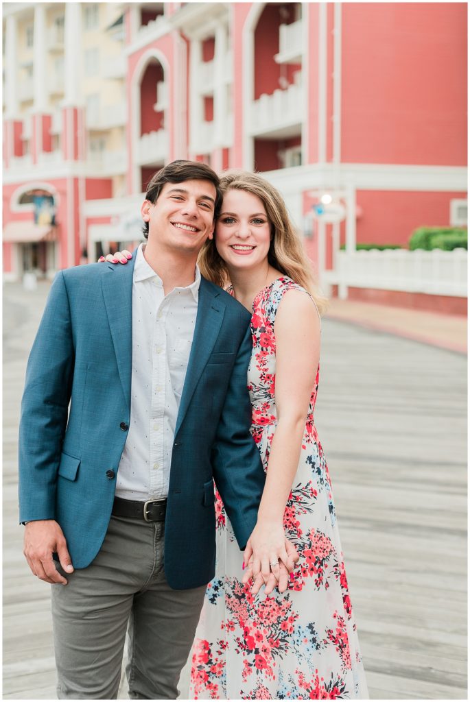 couple snuggled up smiling on Disney's boardwalk for their engagement session