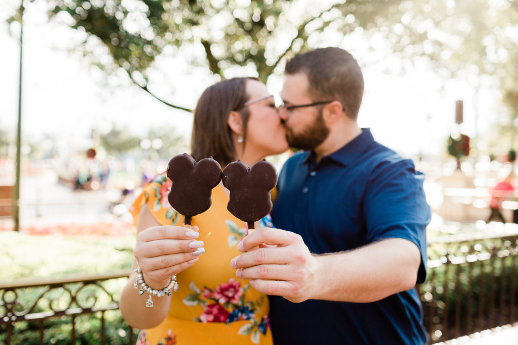 couples kissing and eating Mickey bars at Magic Kingdom Disney photo prop