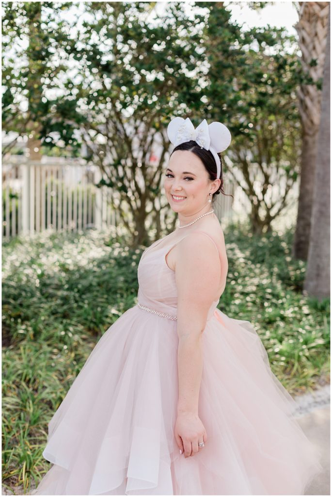 close up of smiling wearing pink bridal gown and wearing Minnie ears
