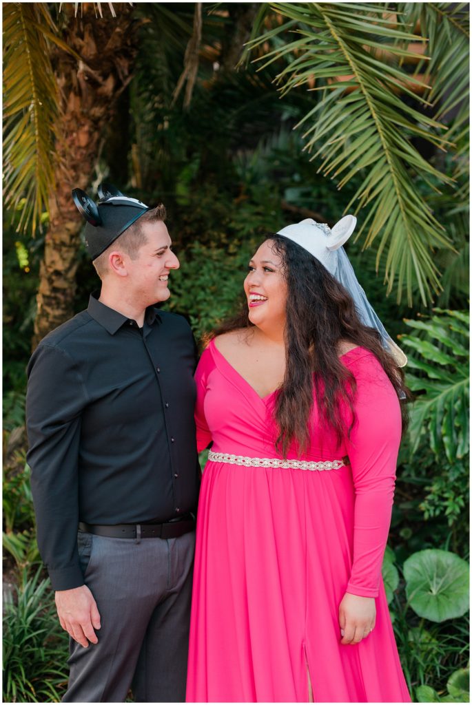 couple smiling looking at each other wearing Mickey and Minnie ear hats