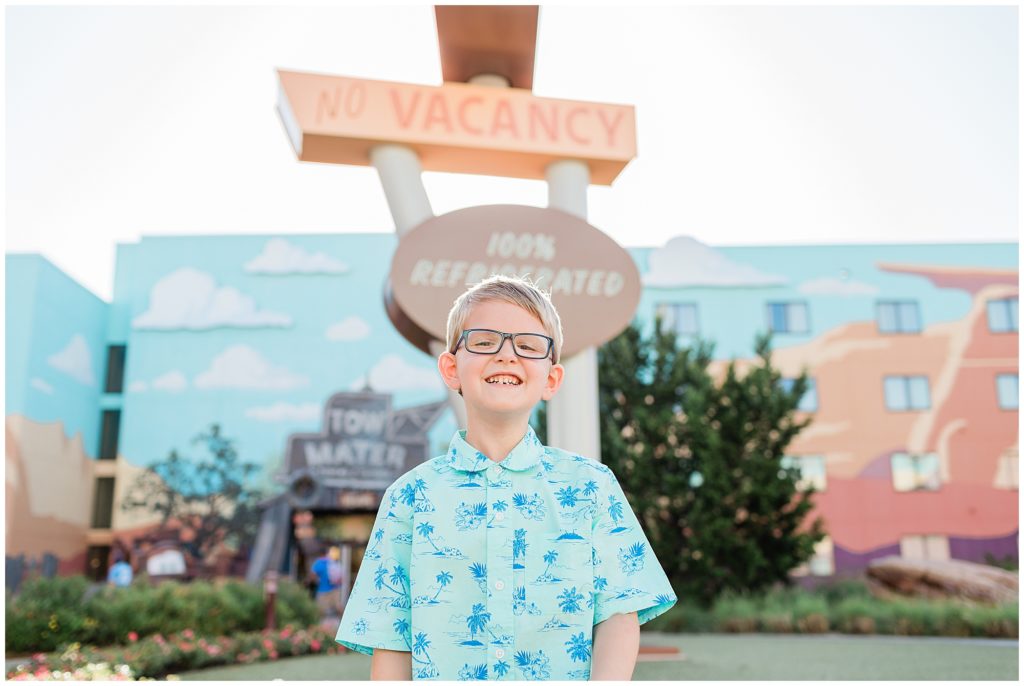 boy smiling in the Cars section infront of the Cozy Cone motel sign