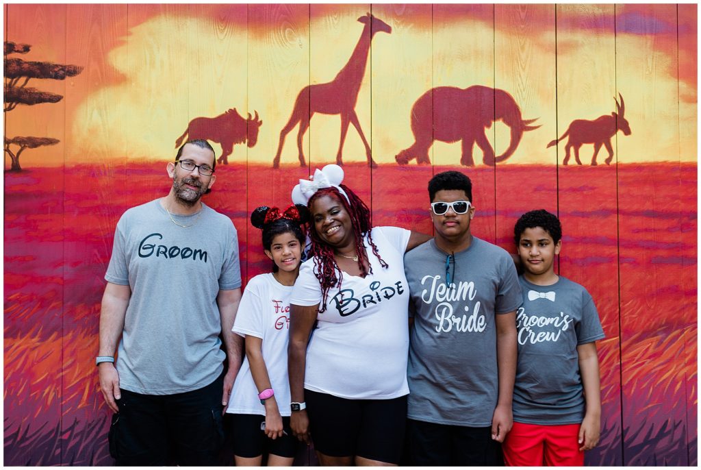 family snuggled together in front of lion king mural