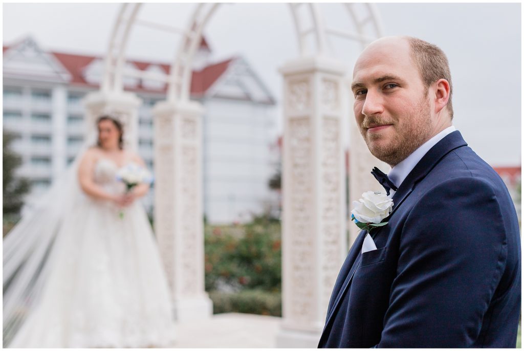 close up of groom looking at camera with bride in the background