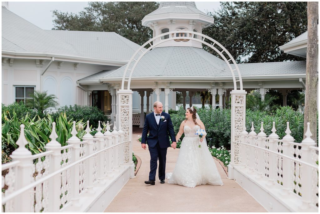 Bride and groom holding hands walking across bridge at Disney's Wedding Pavilion