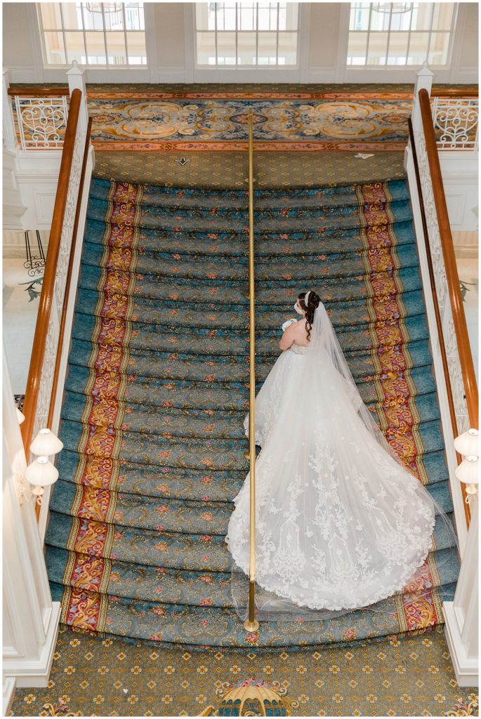 bride in wedding gown on grand staircase looking down